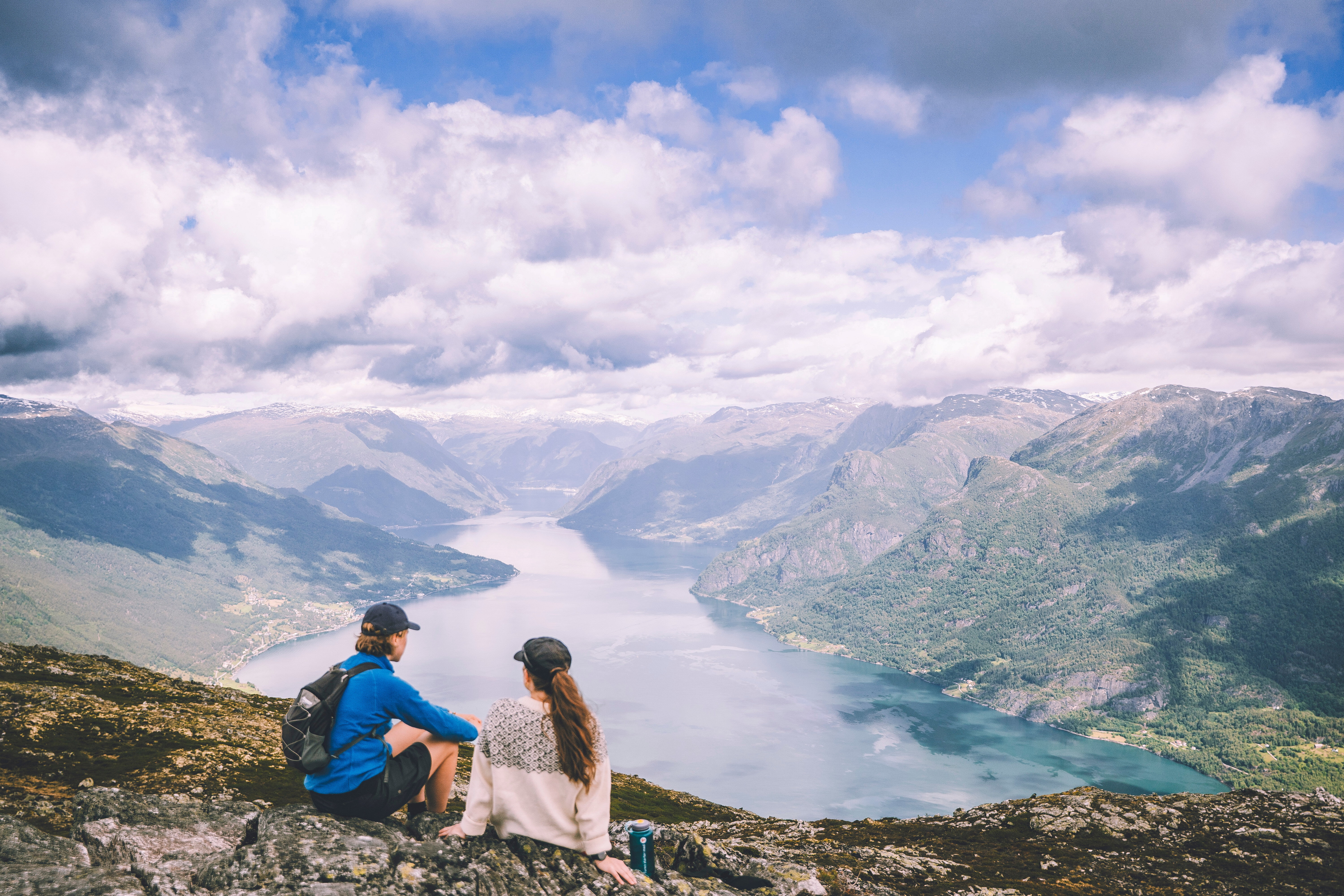 personer som sitter i fjellur og set utover utsikt over fjell og fjord