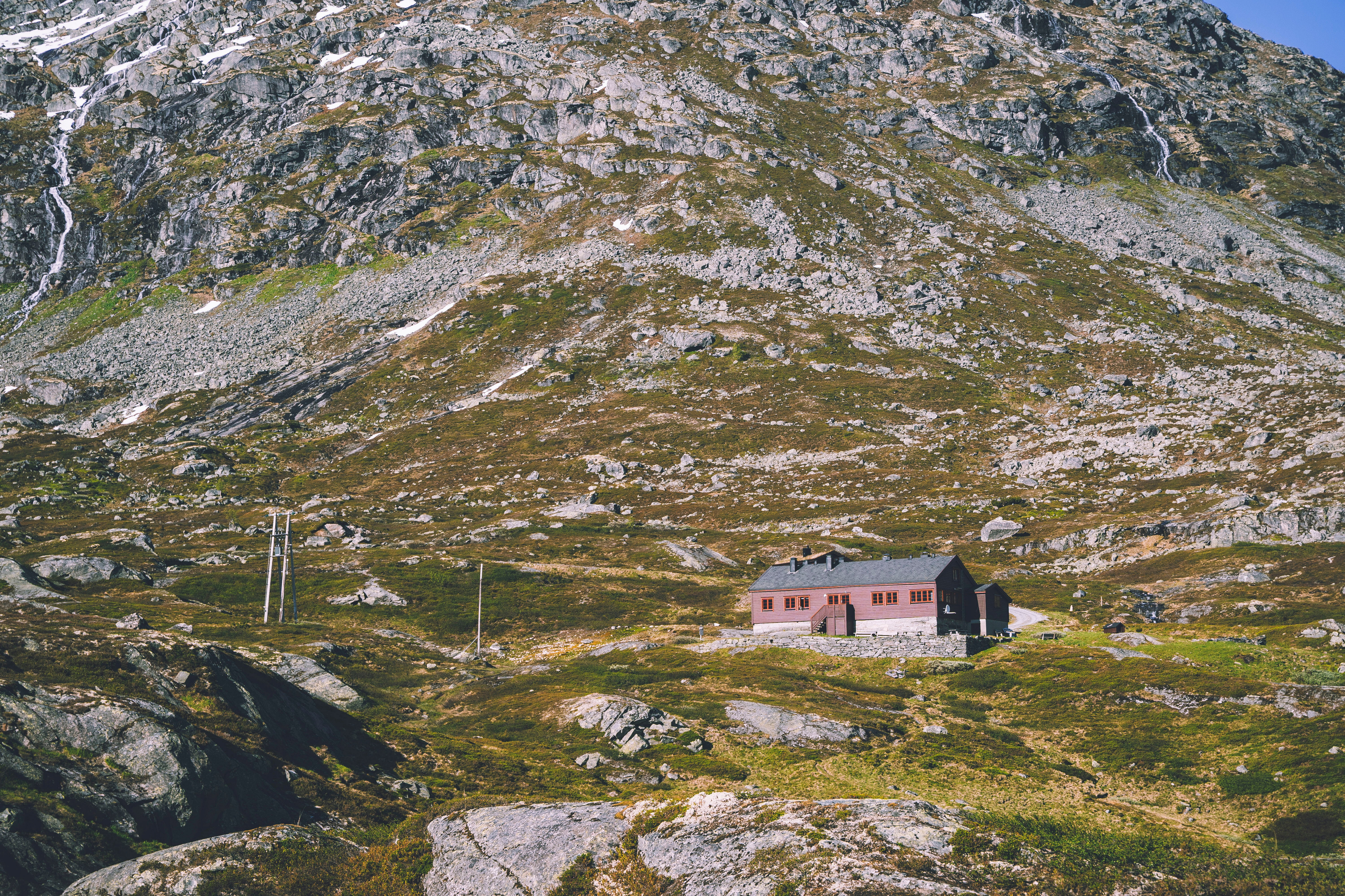 en liten, r&oslash;d hytte i et stort fjellandskap