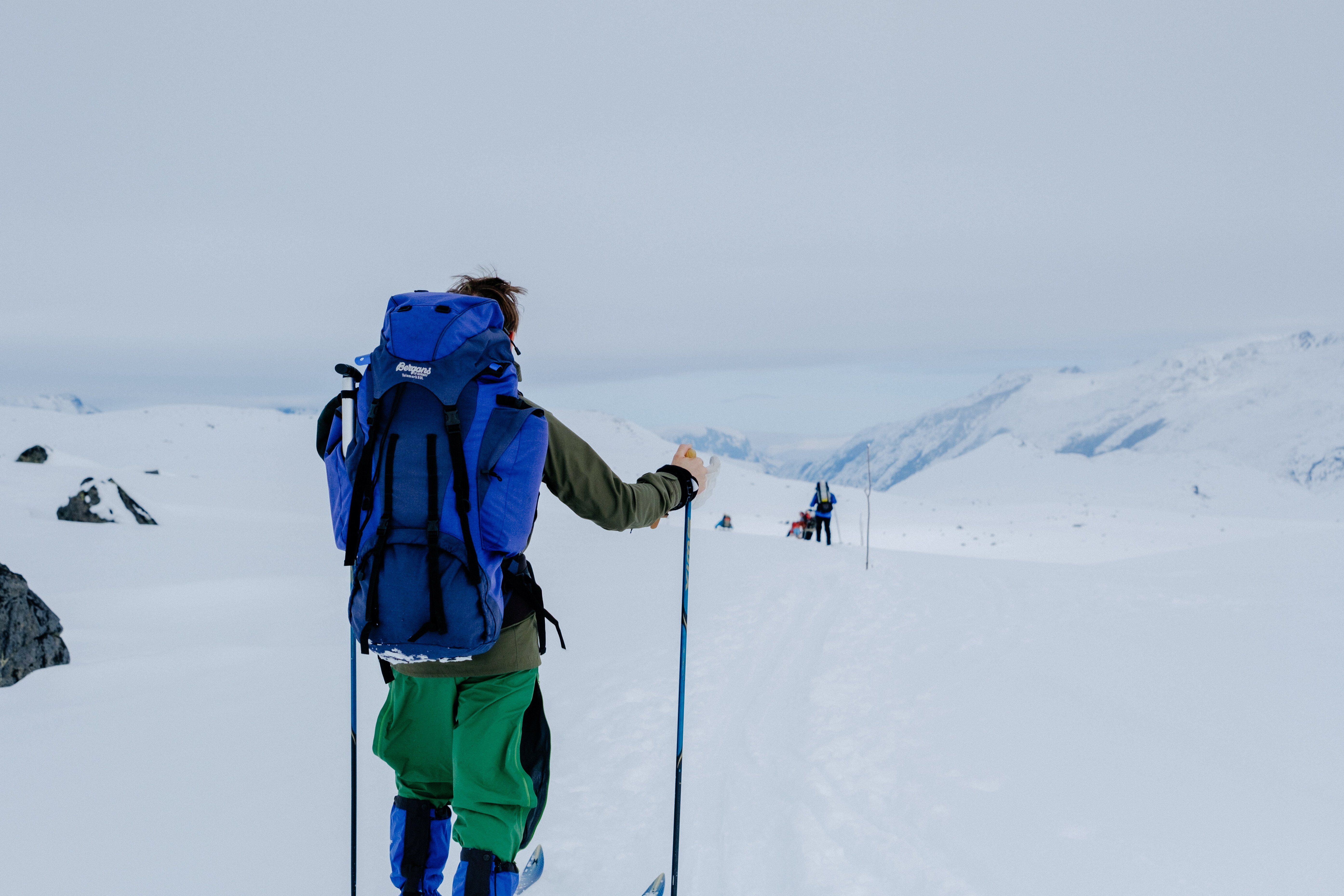 person på ski som står med ryggen til kameraet og har på seg en stor på sekk