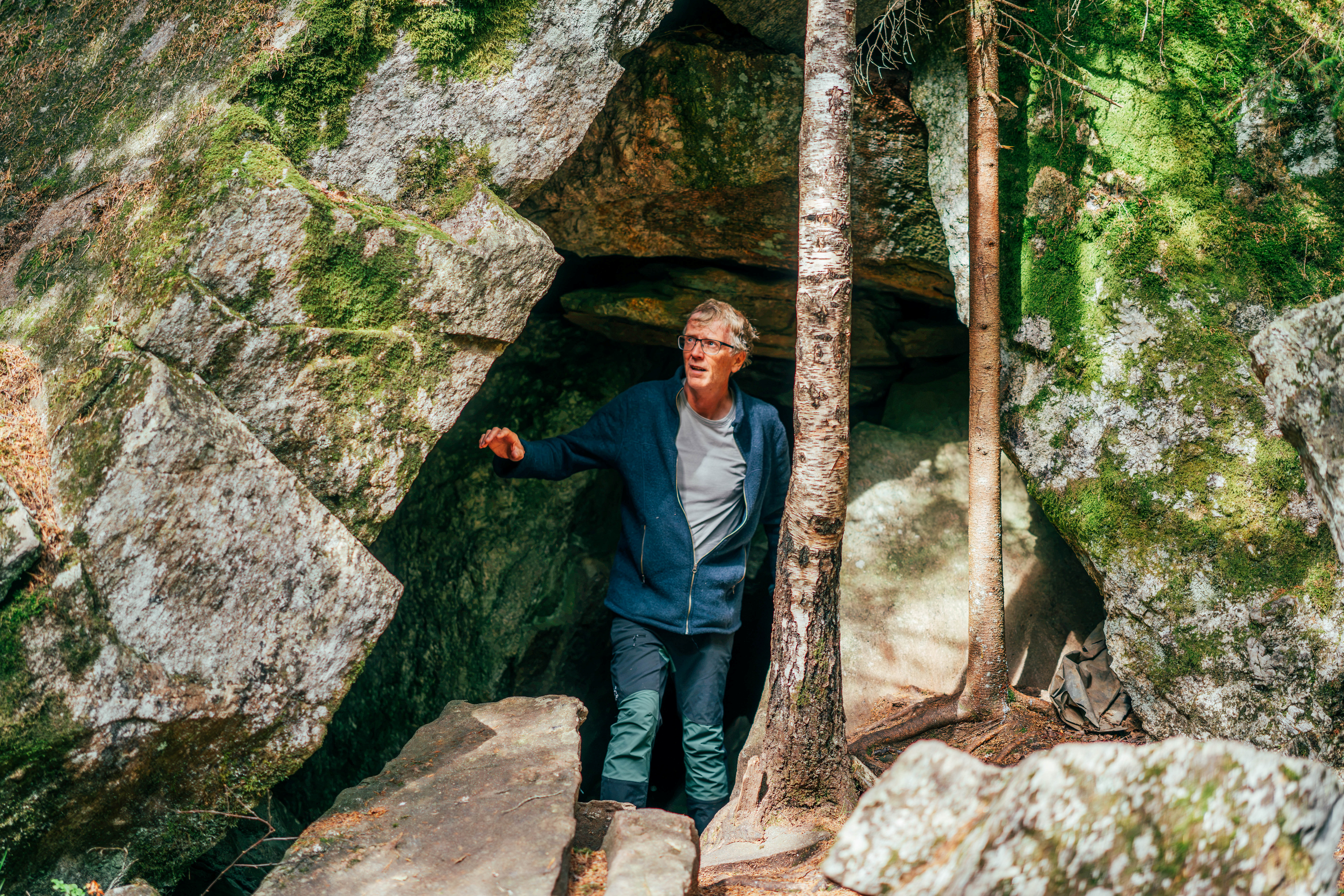 person som st&aring;r inne i en hule i skogen