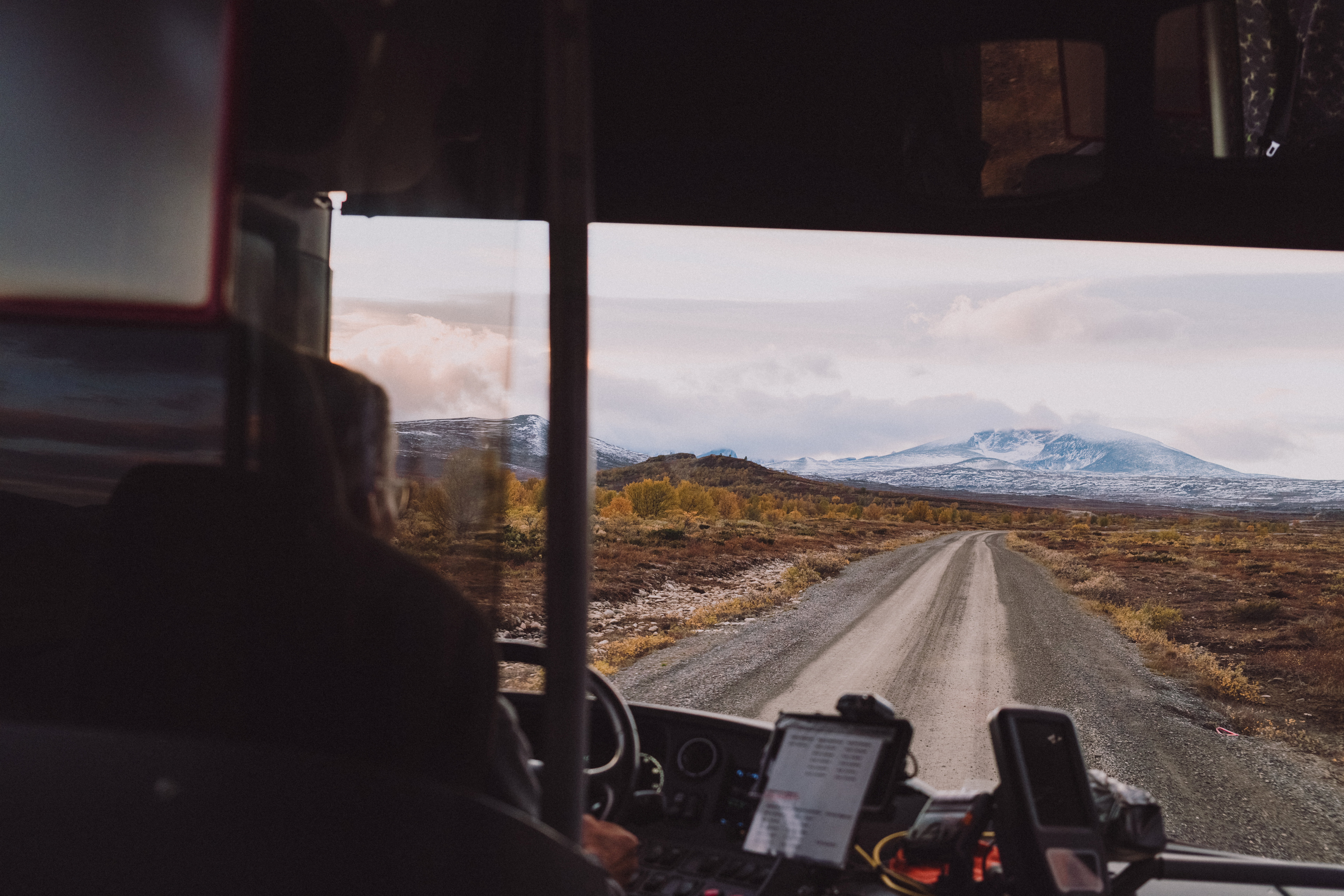 utsikt gjennom bussvindu mot en vei og fjell