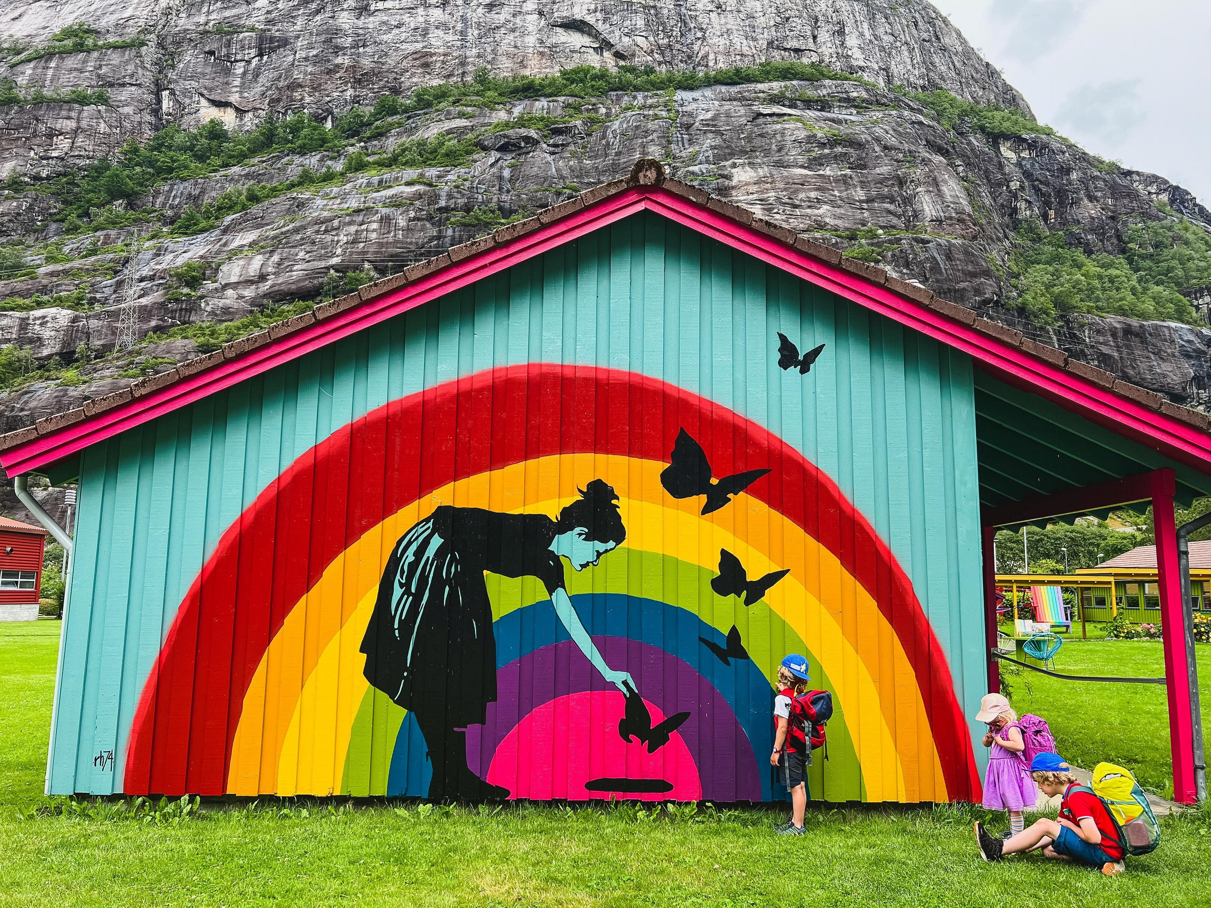 tre barn med tursekk ved fargerik vegg ved lysefjorden