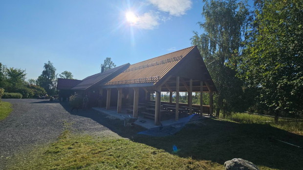Bygg med tilbygg, &aring;pent med tak over bord og benker.