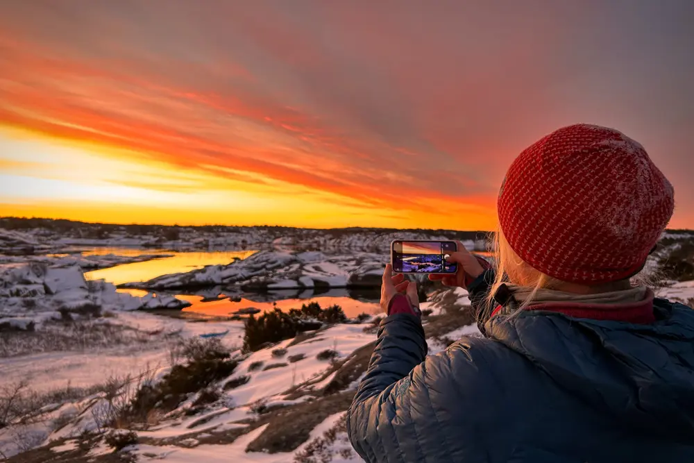 Kvinne med rød topphue ser utover landskap